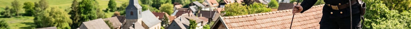 Ein Schornsteinfeger macht einen Kamin auf dem Dorf sauber.