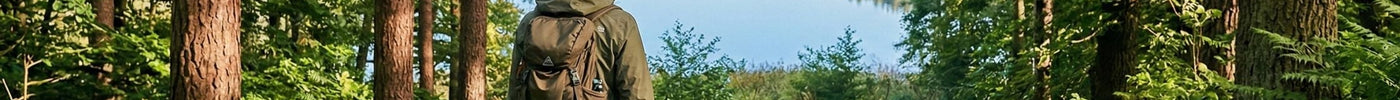 Eine Frau wandert in Brandenburg und steht am Waldrand und schaut sich den See in der Ferne an.