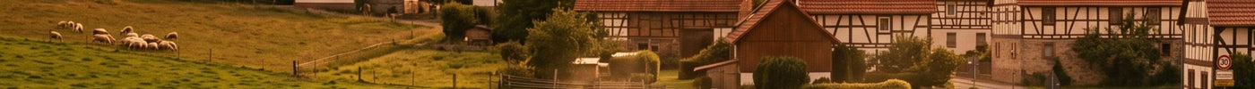 Eine malerische Ansicht eines deutschen Dorfes bei Sonnenuntergang mit Fachwerkhäusern, einer Kirche, einem Traktor auf einem Feld und weidenden Kühen.