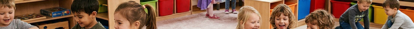 Fröhliche Kinder beim gemeinsamen Spielen, Malen und Bauen in einem hellen, freundlichen Kindergartenraum mit Holzspielzeug.