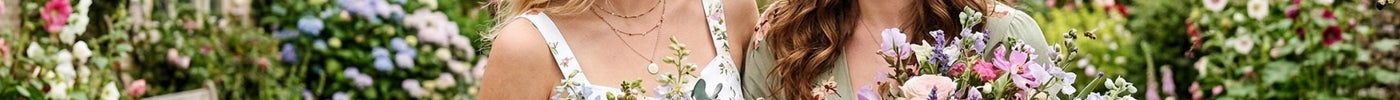 Zwei Frauen feiern den Internationalen Frauentag. Sie lachen und halten schöne Blumensträuße in der Hand.