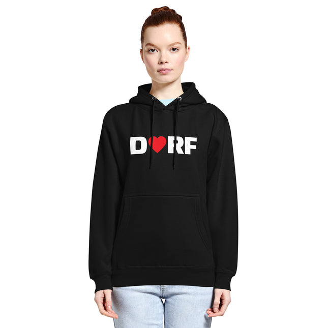 Eine Frau trägt den schwarzen Dorfliebe Frauen Hoodie mit der Aufschrift DORF. Der Buchstabe O ist durch ein rotes Herz ersetzt.