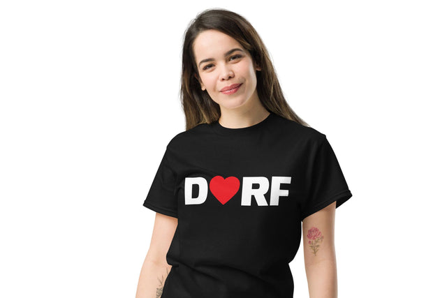 Eine Frau trägt das schwarze Dorfliebe Frauen T-Shirt mit der Aufschrift DORF. Der Buchstabe O ist durch ein rotes Herz ersetzt.